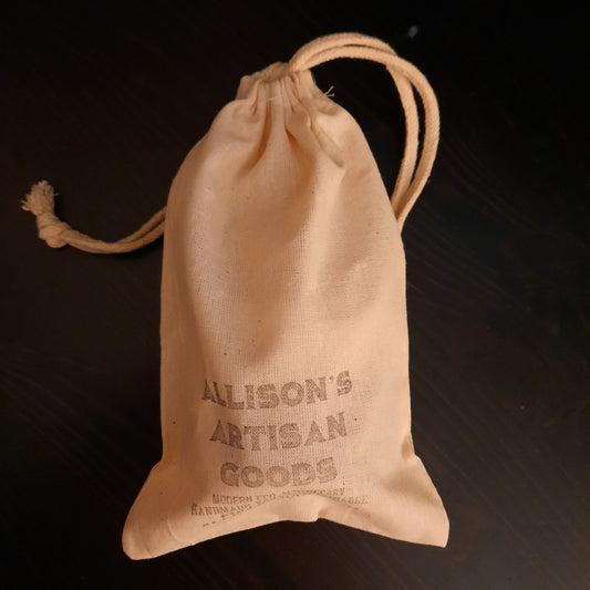 cream colored cloth drawstring bag on dark wood background