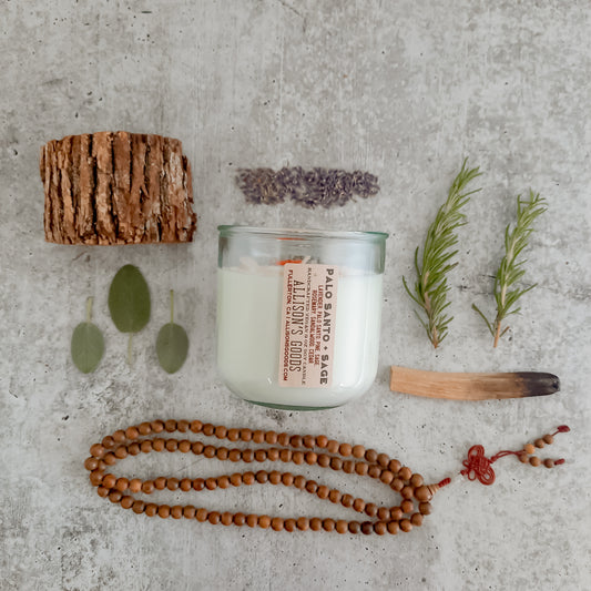 flat lay of sustainable vegan candle jar on cement with moss palo santo sage lavender and sandalwood mala beads