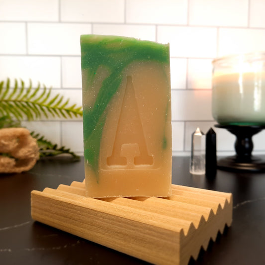 handcrafted vegan soap bar organic oils
on wood soap dish
with moon background spooky dark apothecary style
in bathroom on tile