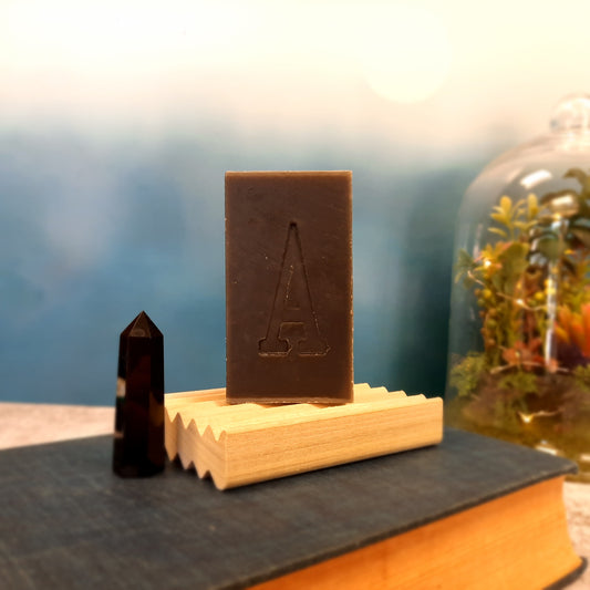 handcrafted vegan soap bar organic oils
on wood soap dish
with moon background spooky dark apothecary style
in bathroom on tile