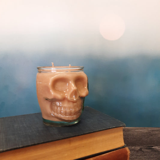 skull candle on stack of books with blue backdrop
