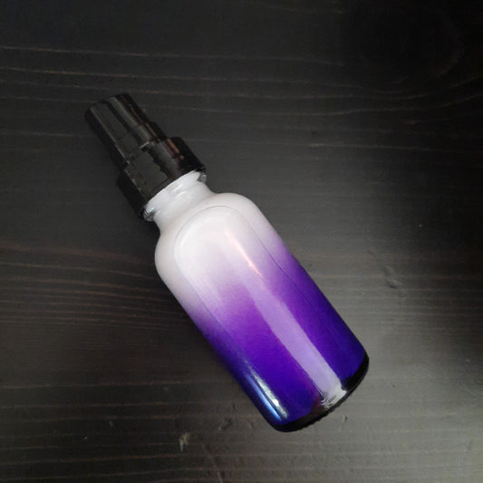 purple glass bottle on stack of vintage books with green plants