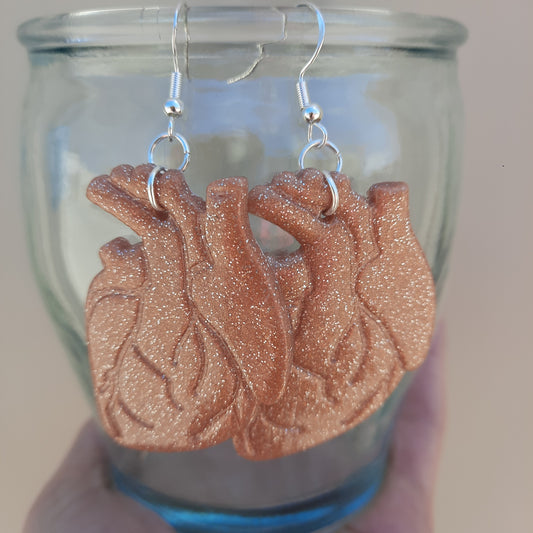 rose gold heart earrings hanging on glass