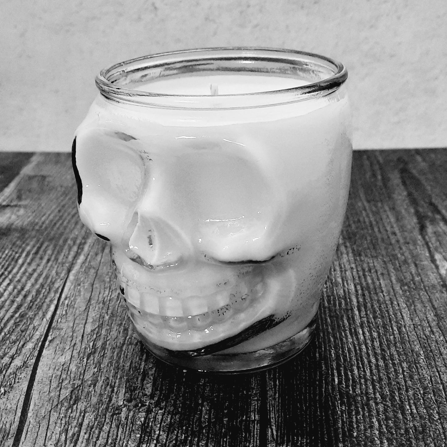 black and white photo of skull candle on wood
