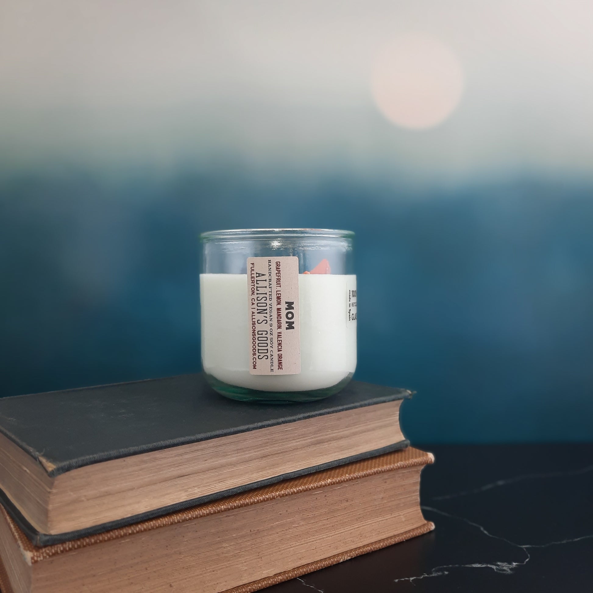 candle on stack of antique books in front of moon