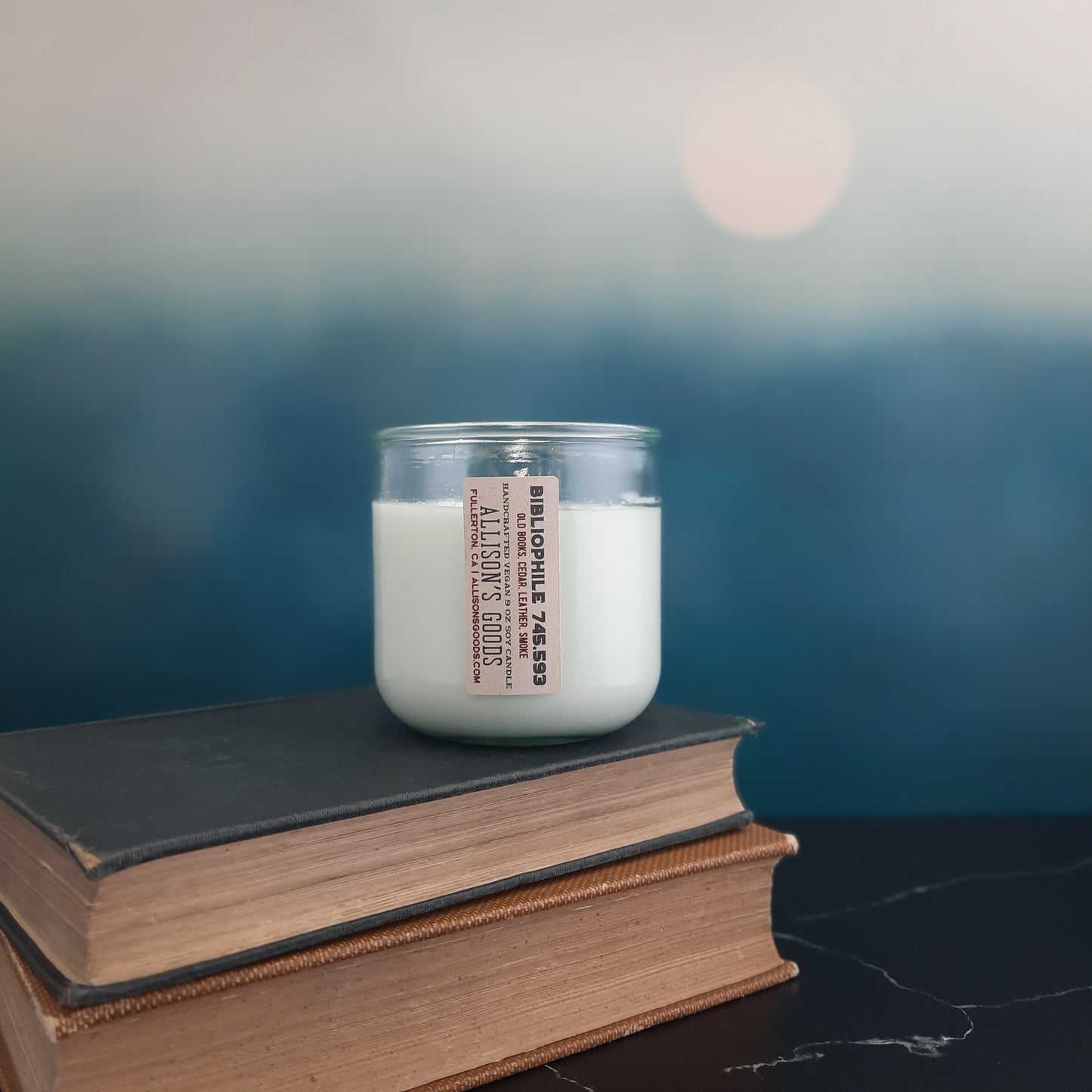 vegan sustainable handcrafted candle on antique books with moon