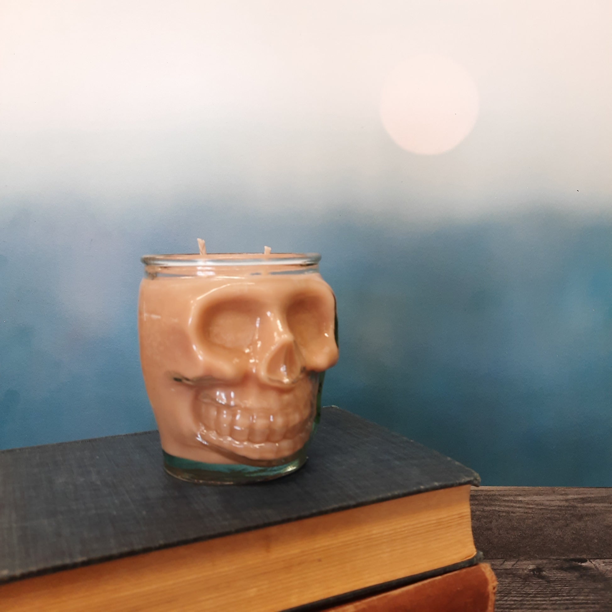 skull candle on stack of books with blue backdrop