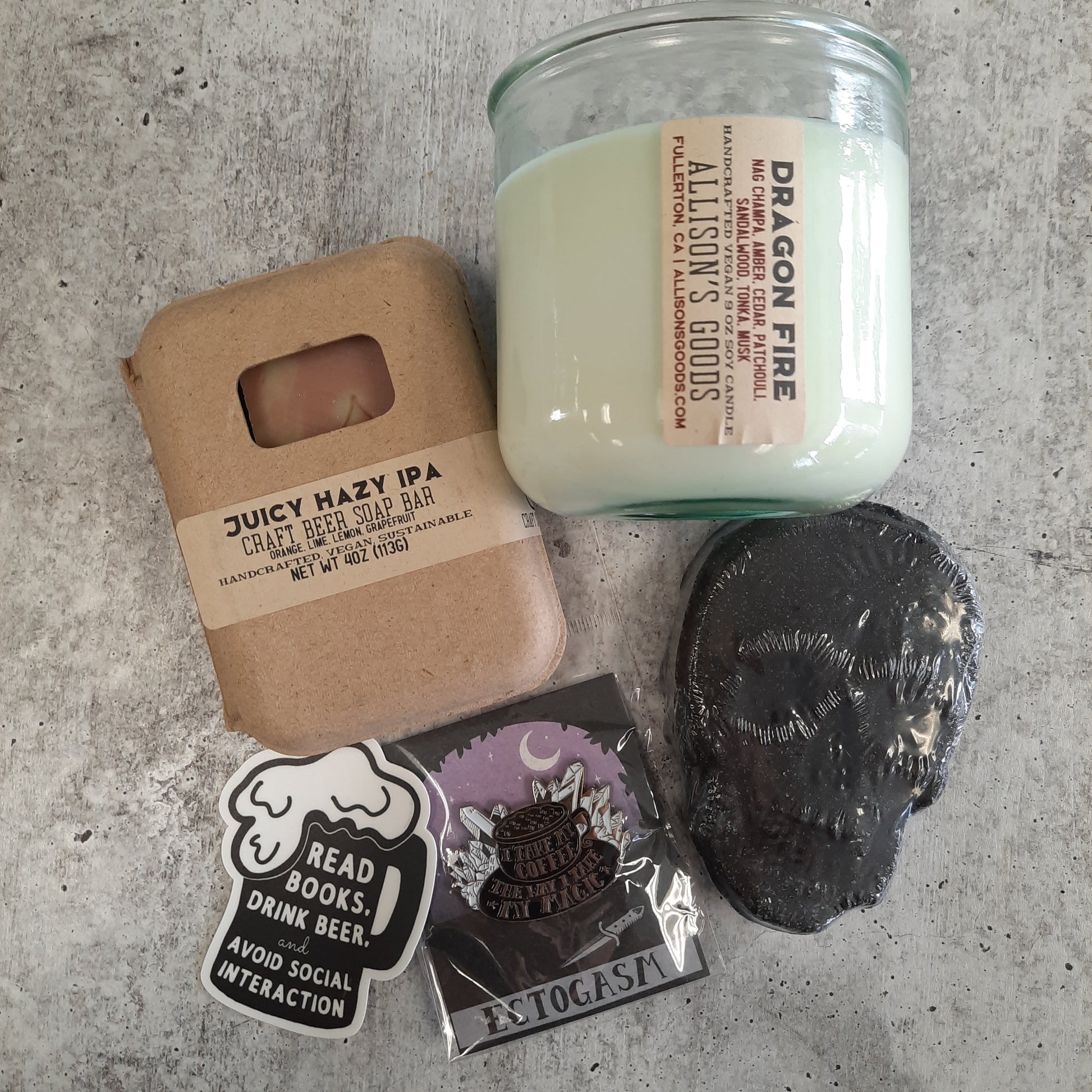 concrete flatlay of dragon fire candle with soap bath bomb and pins
