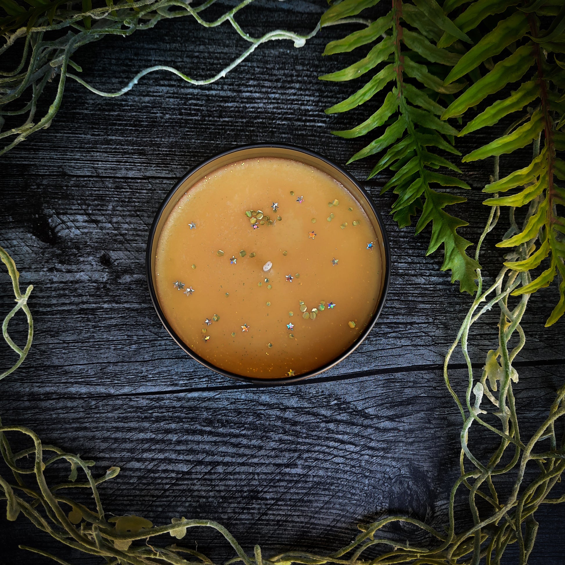 flatlay of vegan candy corn candle with sparkles glitter and stars