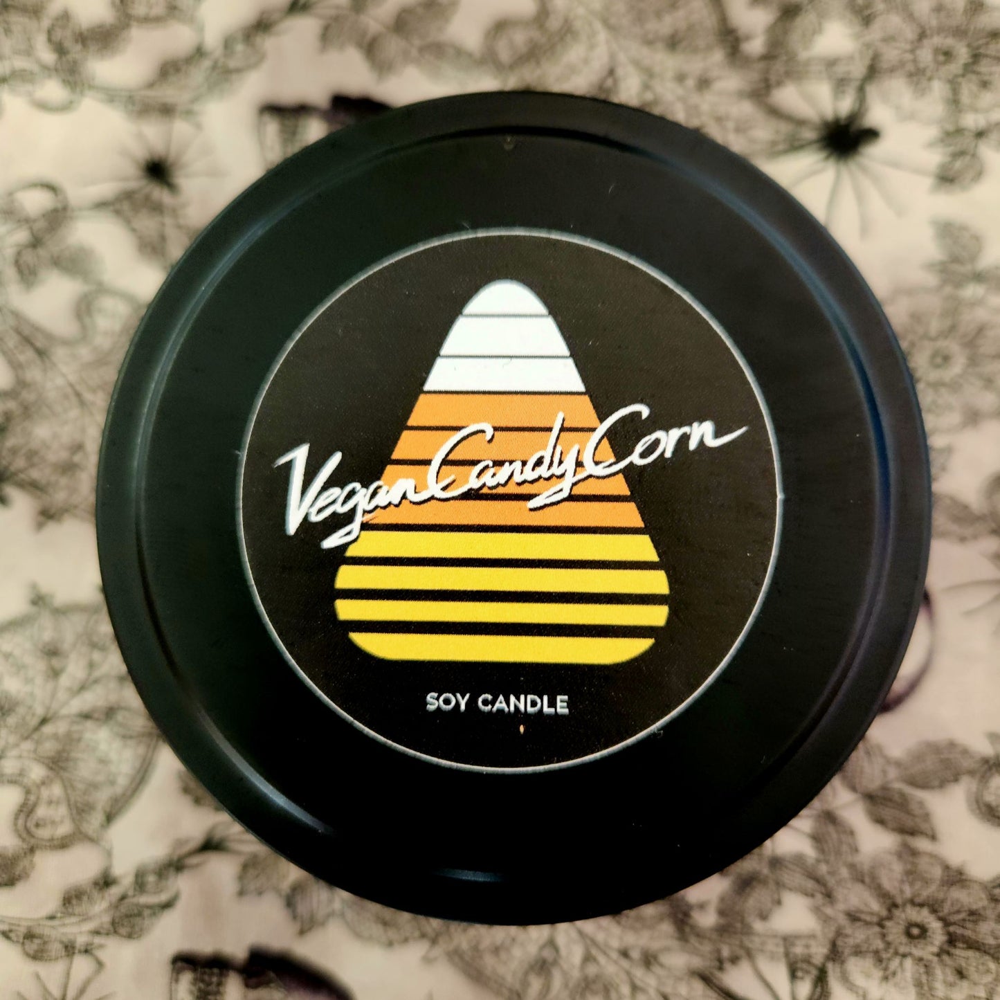 vegan candy corn logo on black tin candle lid