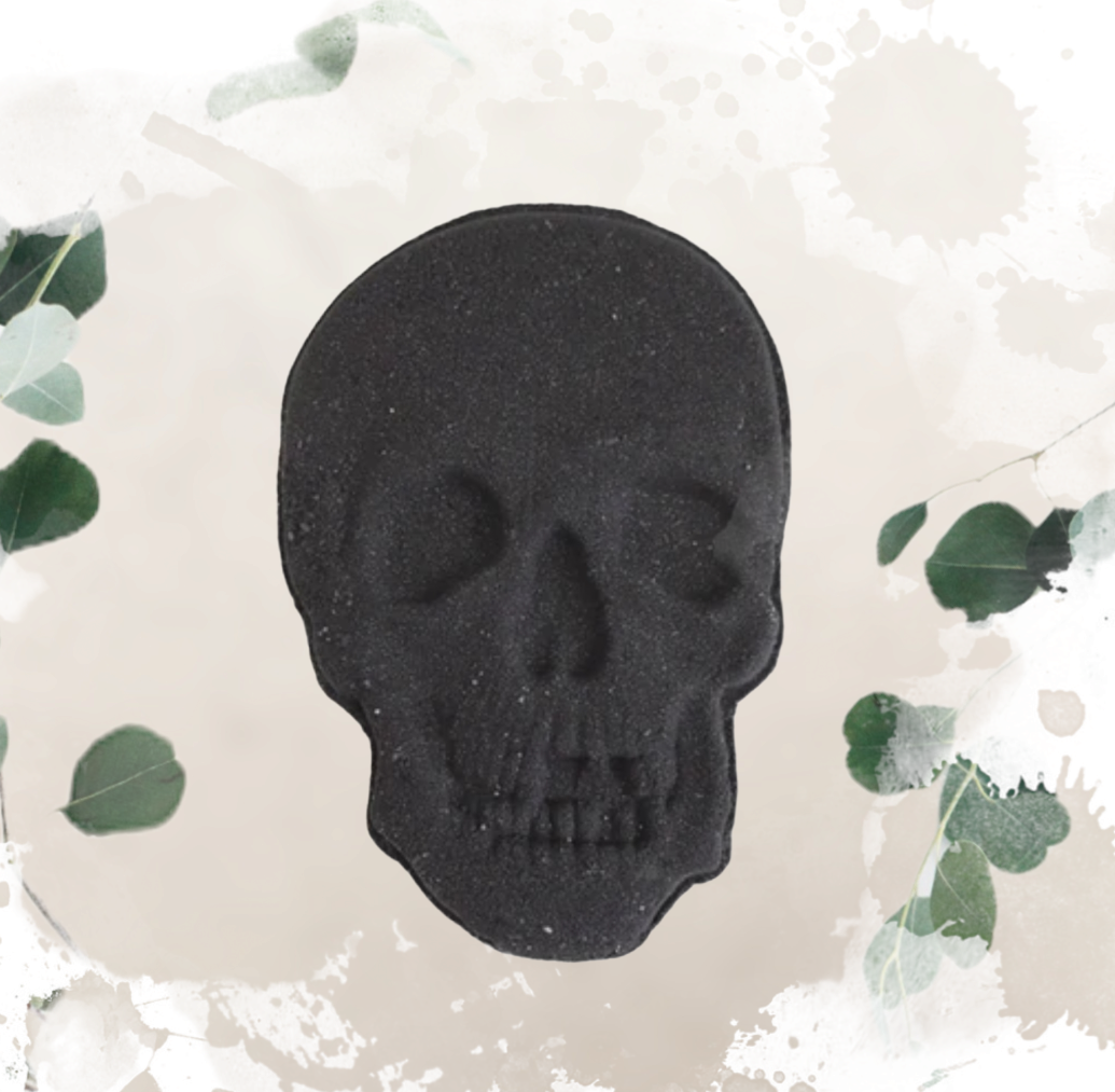 black skull bath bomb on white background with eucalyptus leaves